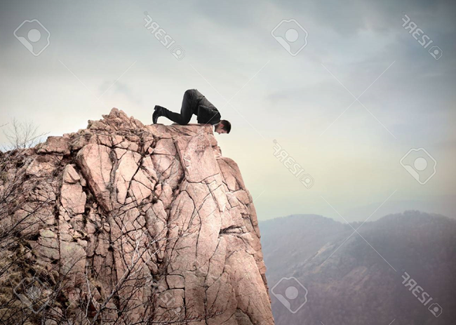 13037665-young-businessman-kneeling-on-a-dangerous-peak-and-looking-downwards.png