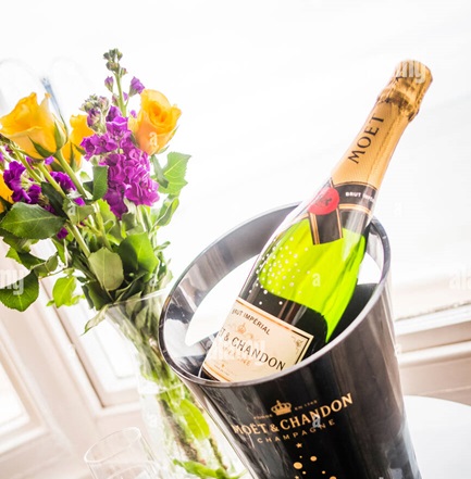 a-bottle-of-moet-chandon-champagne-on-ice-with-flowers-in-a-hotel-E10TYJ.jpg